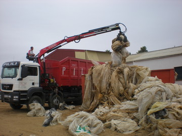 Camión con grúa pulpo cargando plástico agrícola en Huelva